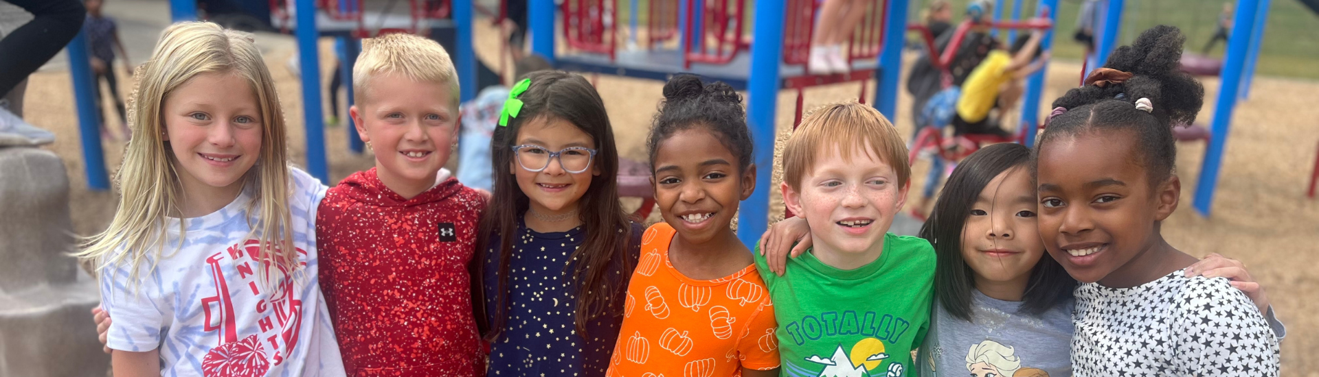 7 KME students standing arm in arm at recess with smiles on their faces